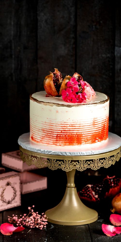 creamy cake in white with red decoration garnished with pomegranate and flowers